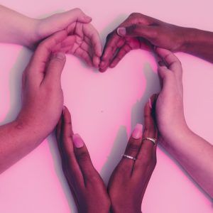 Image depicts six hands, of different skin colours, each cupped and forming a silhouette of a heart.